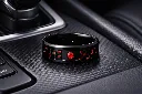 black-ceramic-ring-with-red-stone-inlay-carbon-fiber-in-car.webp